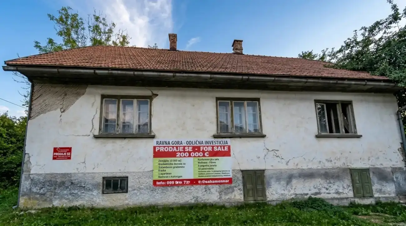 Stara kuća u Ravnoj Gori s oštećenom fasadom i transparentom za prodaju nekretnine.